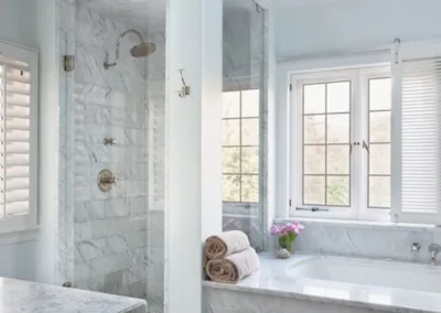 A white bathroom with a skylight and marble floors.