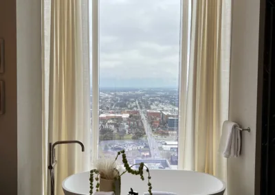 A bathroom with a bathtub and a view of a city.