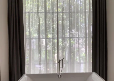 A bathroom with a bathtub and a large window.