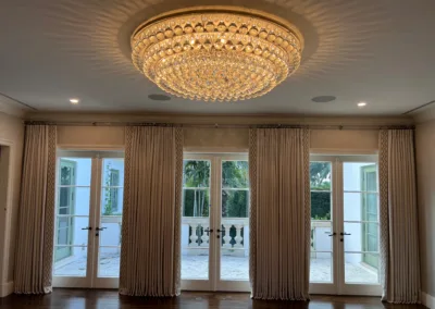 A room with a chandelier and sliding glass doors.