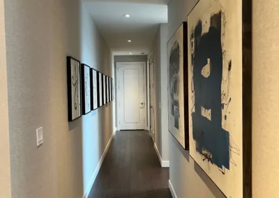 A hallway with framed art and hardwood floors.