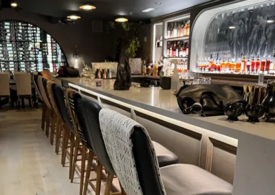 A bar with stools and a glass of wine.