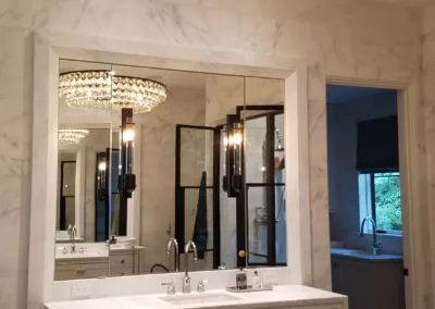 A bathroom with marble counter tops and a chandelier.