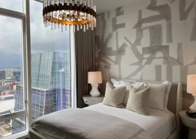 A bedroom with a large window overlooking a city.
