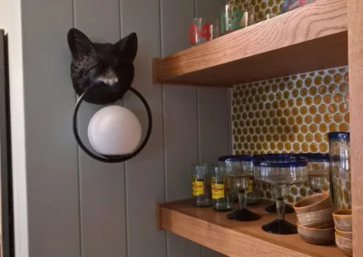 A cat head hanging on a shelf in a kitchen.